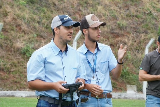 Dois homens operando drone por controle remoto durante treinamento da DJI Academy